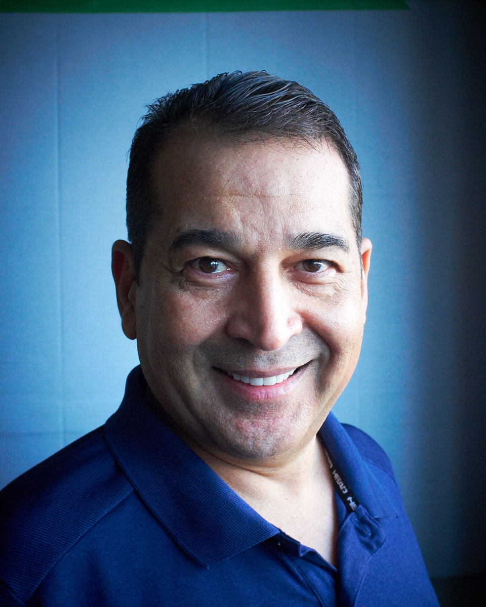 Smiling man in blue shirt with short hair.