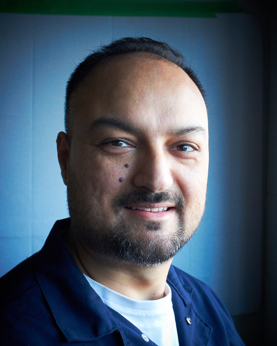 Smiling person in a blue shirt, close-up portrait.
